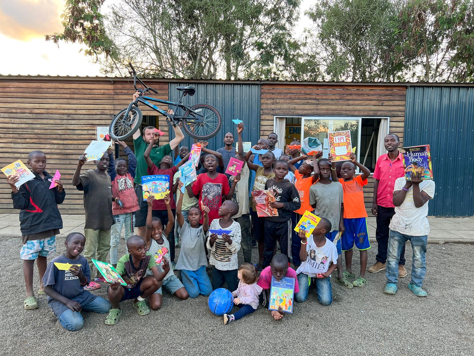 Boys holding books and a bicycle during an Embrace centre programme