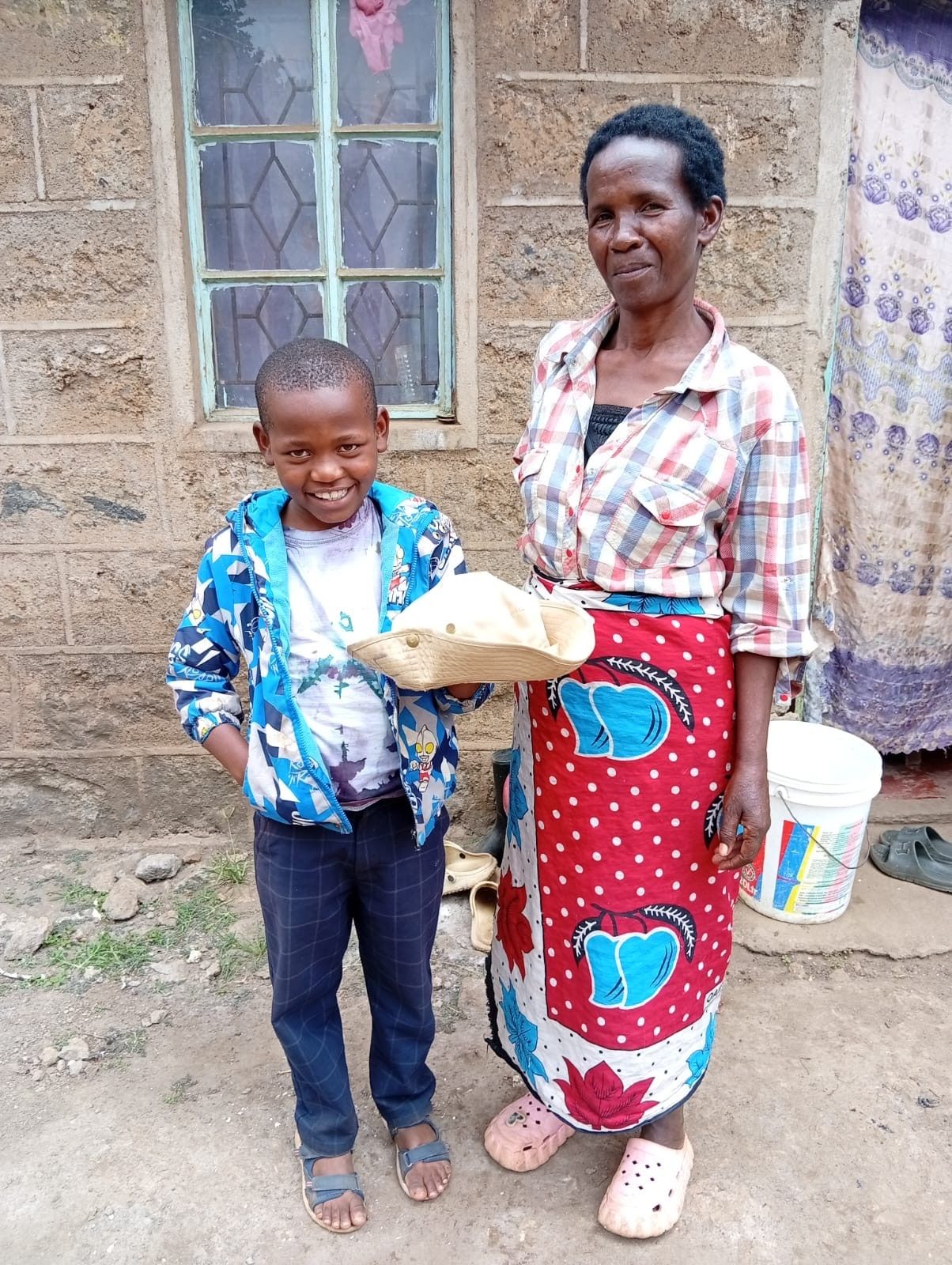A boy standing with a caregiver during a reintegration home visit