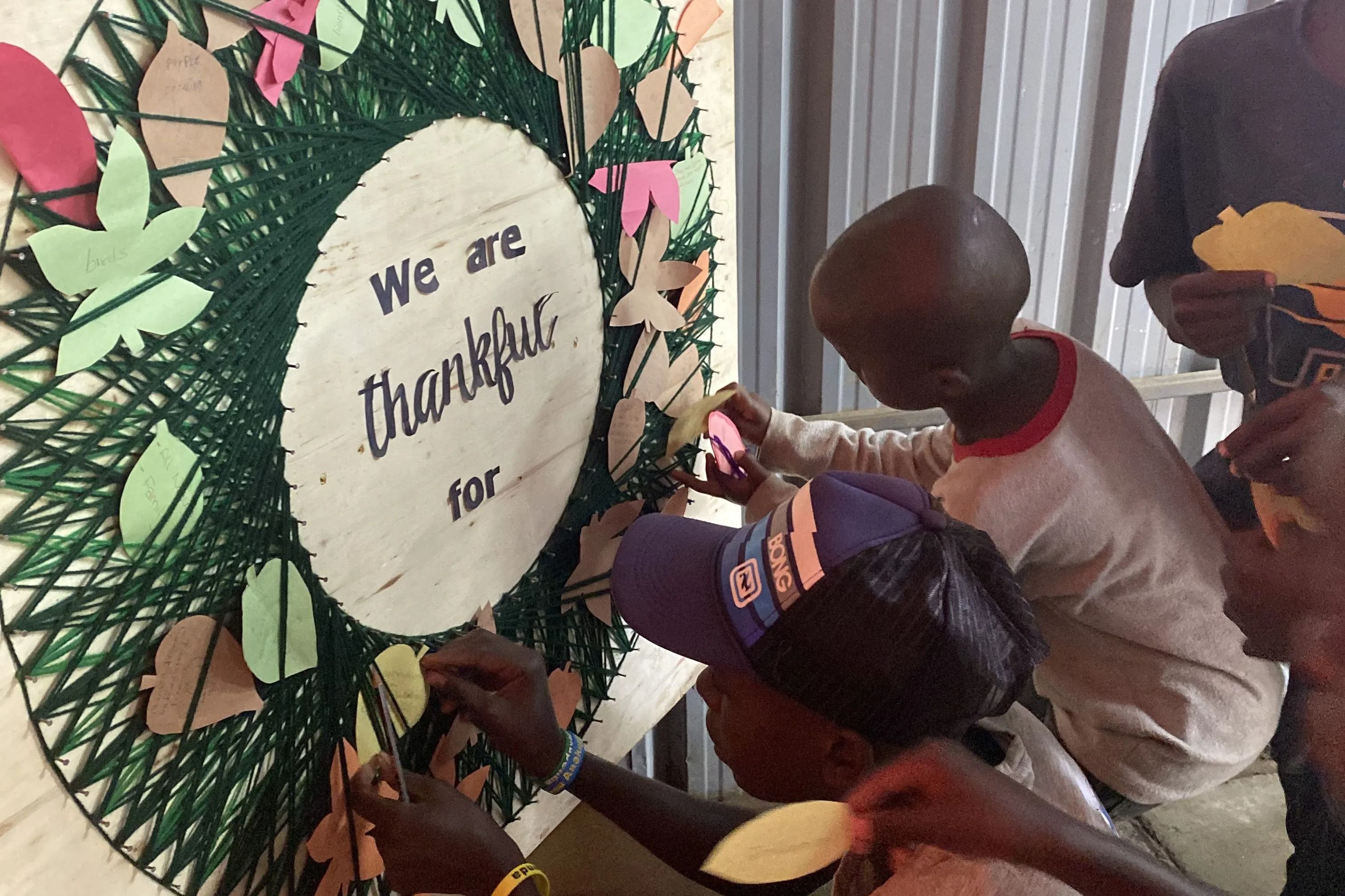 Boys adding paper leaves to a Thanksgiving gratitude board during a Centre program activity