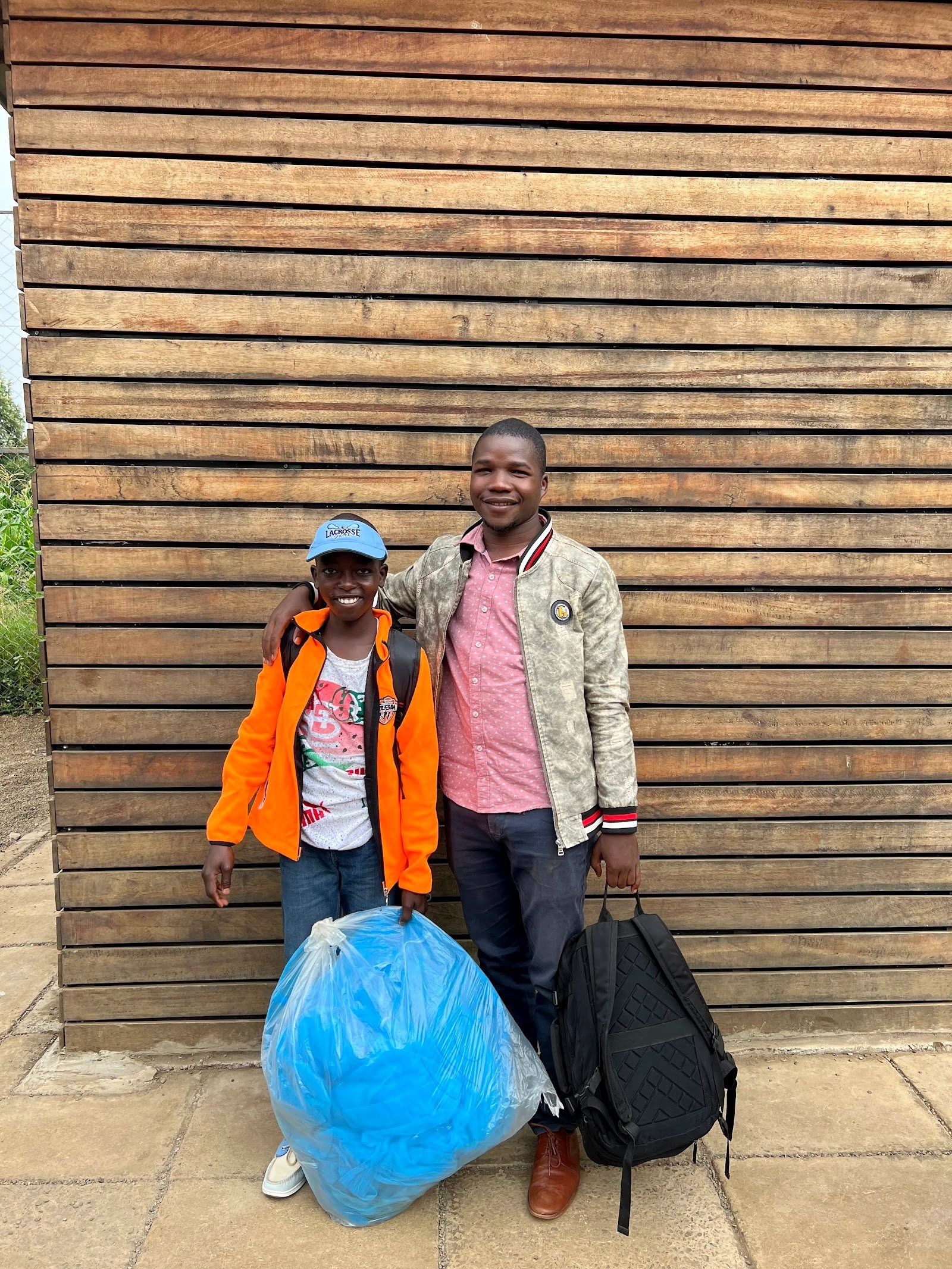 A reintegrated boy standing with a caregiver and packed belongings during the journey home