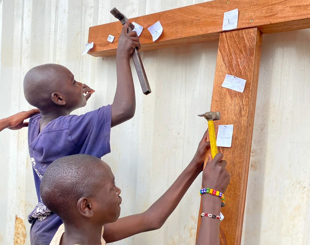 Boys placing prayers on a wooden cross at Easter